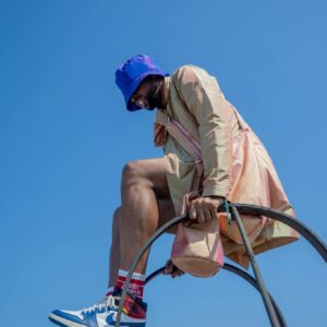 Dynamic low-angle shot of a man in colorful urban fashion against a clear blue sky.
