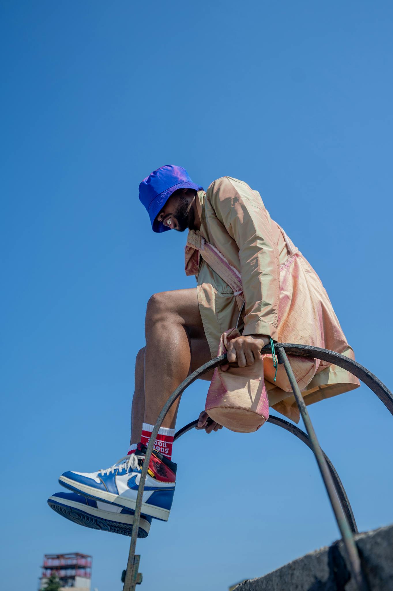 Dynamic low-angle shot of a man in colorful urban fashion against a clear blue sky.