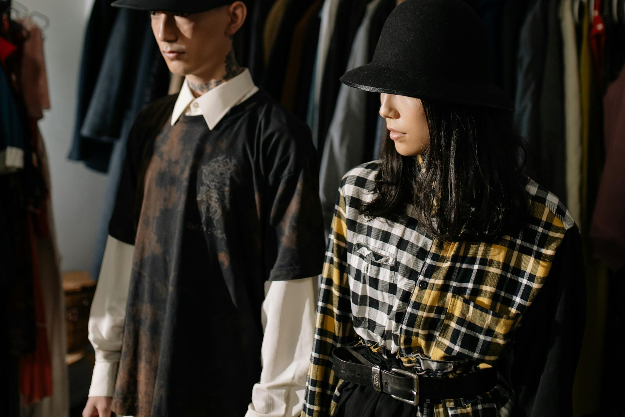 Fashion-forward man and woman wearing stylish hats and plaid shirts in a clothing store.